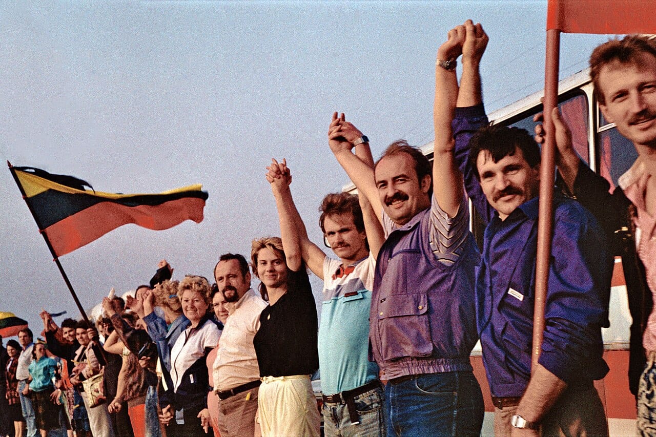 A line of people holding hands and flying Lithuanian flags.