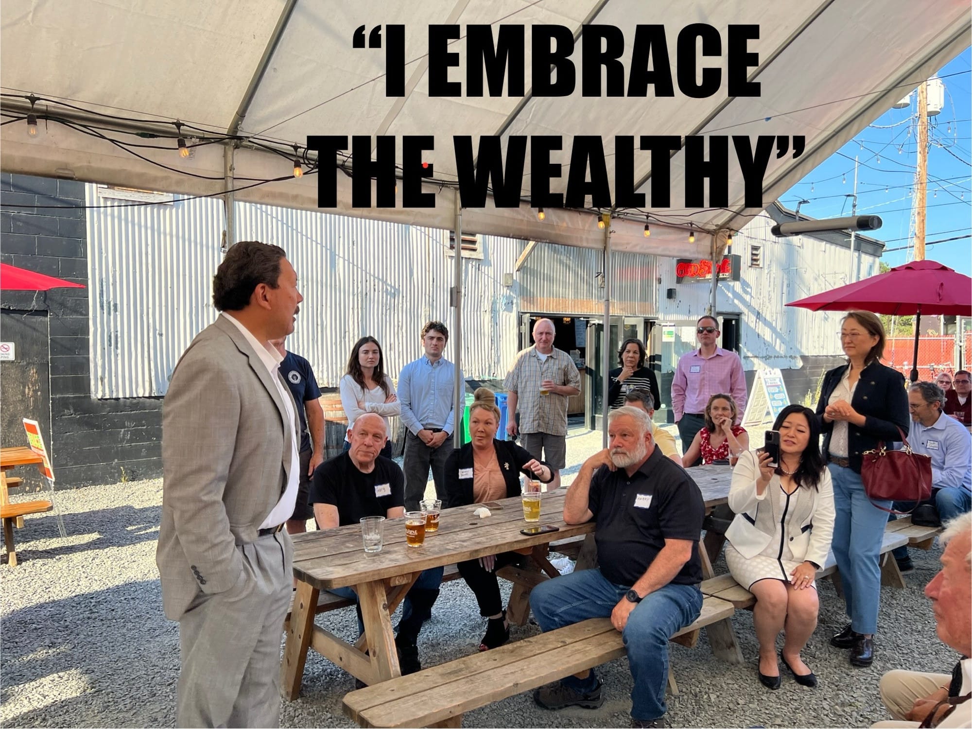 Bruce Harrell speaks to a group of supporters sitting outside at a brewery.