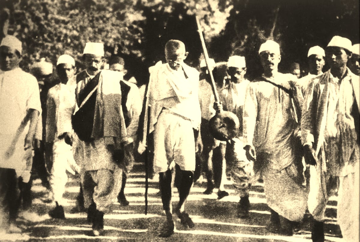 Mahatma Gandhi, in a simple tunic and sandals, leads other Indians on a march to the sea.