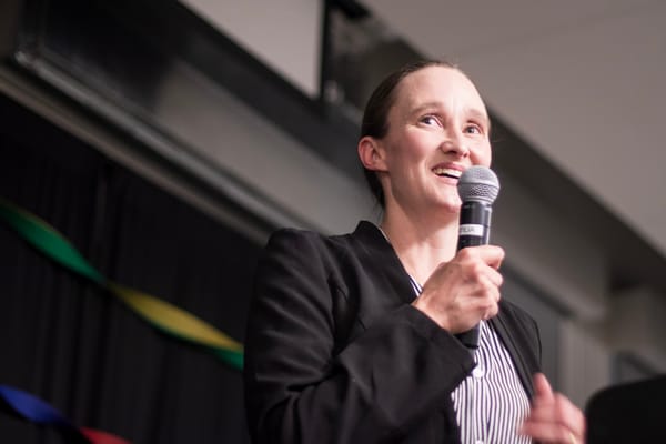 Katie Wilson, with a smile on her face, speaks into a microphone on election night.