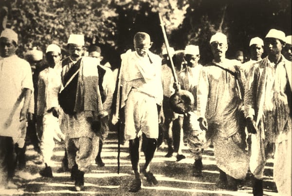 Mahatma Gandhi, in a simple tunic and sandals, leads other Indians on a march to the sea.